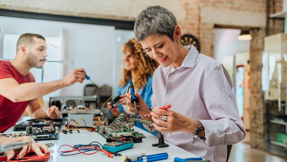 Une femme mature répare un objet dans un atelier.