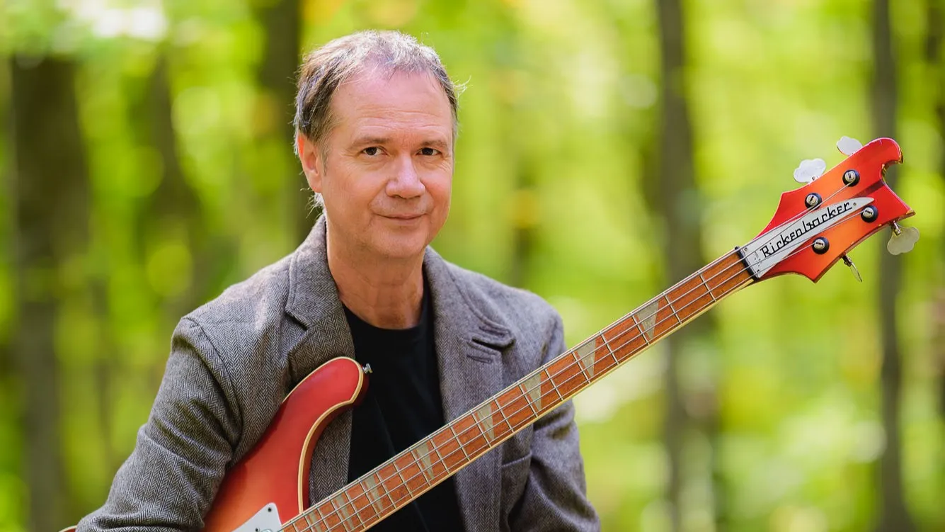 François Pérusse assis dans la forêt avec une basse.