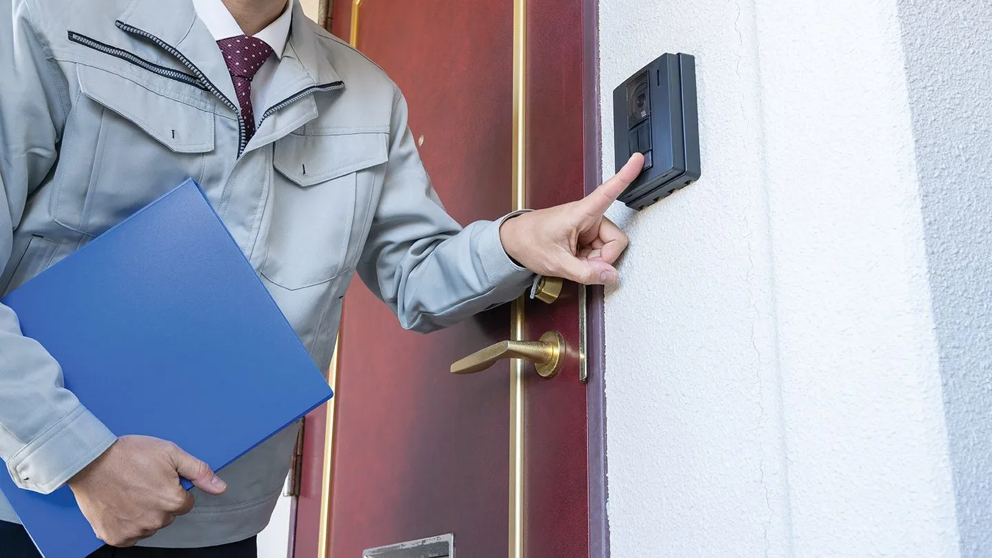 Un vendeur itinérant sonne à une porte en tenant des dossiers.