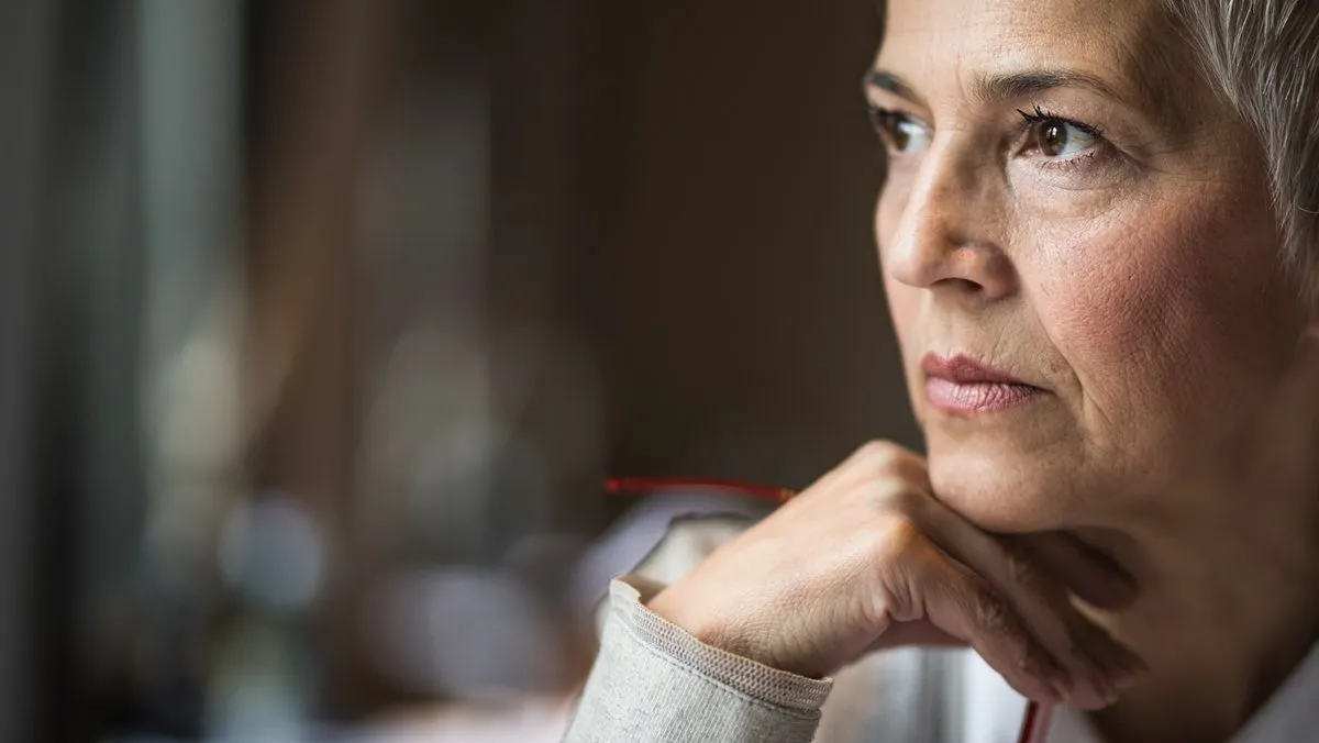 Gros plan du visage d'une femme qui regarde au loin en réfléchissant.