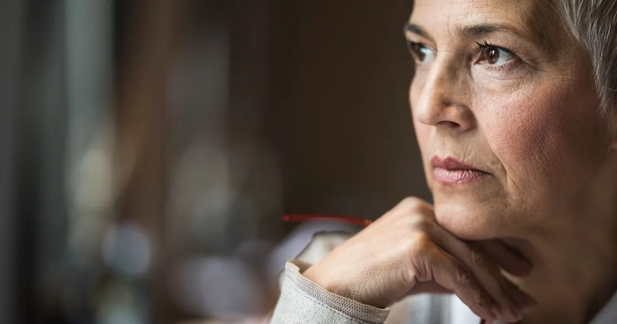 Gros plan du visage d'une femme qui regarde au loin en réfléchissant.