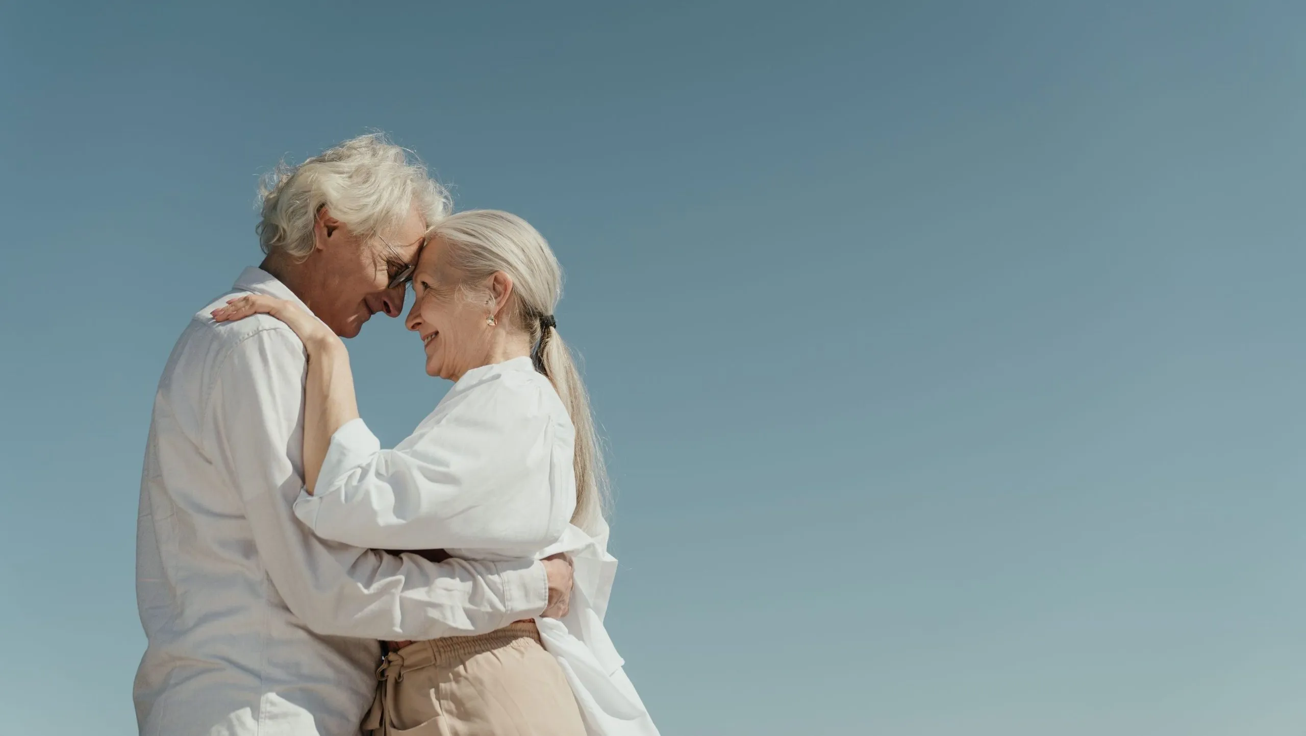 Un couple hétérosexuel s'embrasse sous un ciel bleu.