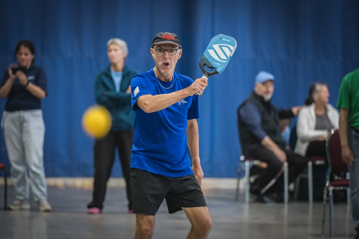 Joueur de pickleball effectuant un coup lors d’un match en gymnase.